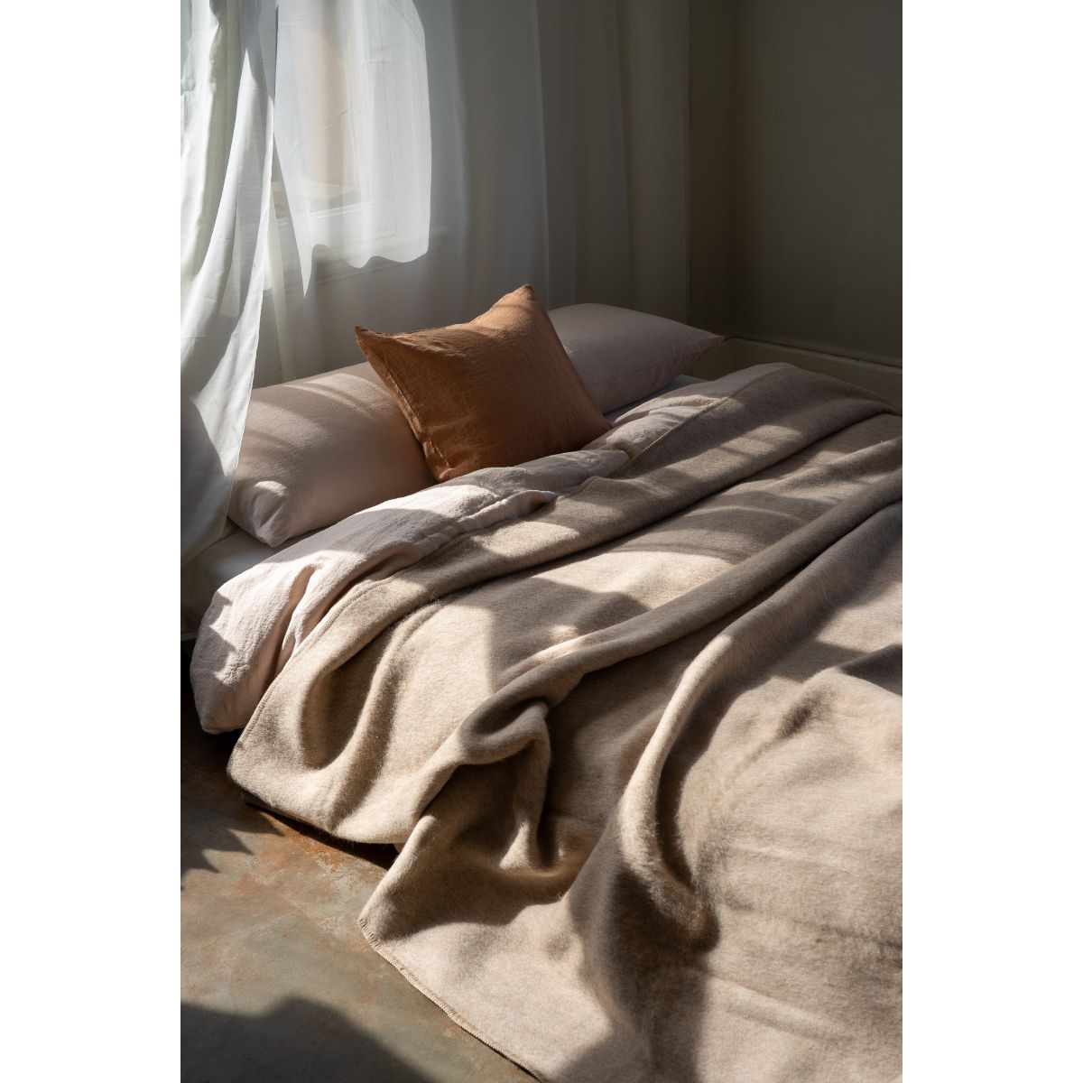 Cozy bed with beige blanket and pillow in a softly lit room