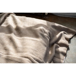Beige blanket draped over a surface with a neutral background