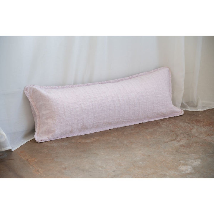 Pink pillow on a textured surface with a light curtain background